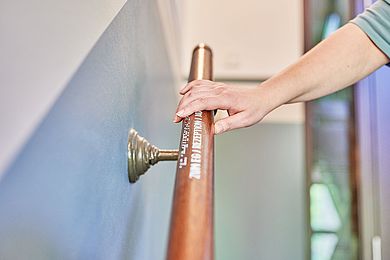 Hand erfühlt den Handlauf im Hotel mit Brailleschrift