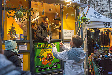 Bude "Kitchen Riot", Burritos, eine freundlich schauende Frau reicht einen Burrito heraus