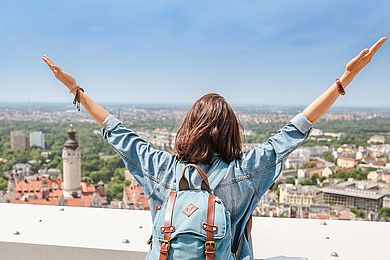 Eine Frau steht auf dem MDR-Turm in Leipzig und schaut über die Stadt