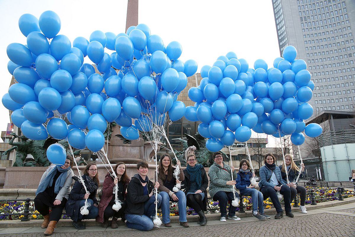 Mitarbeitende mit blauen Luftballons anlässlich des Welt-Autismus-Tages