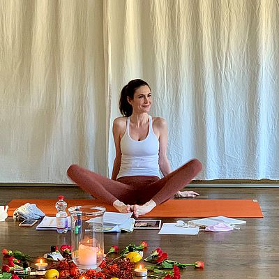 Yoga Trainerin Sandra Schunck sitzt auf einer Yoga-Matte im Schneidersitz