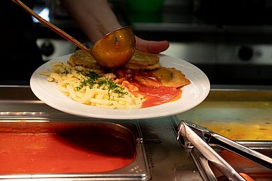 Essen wird ausgehändigt, das Gericht wird mit Soße übergossen