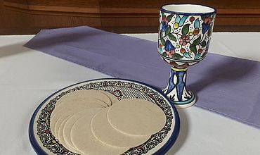 Das Bild zeigt den Altar in Philippus. Darauf ist ein weißes Tuch. Darauf steht ein farbenfroher Kelch und ein bunter Teller, auf welchem Hostien zu sehen sind.